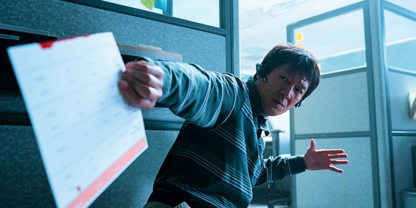Ke Huy Quan holding a desk calendar in an action pose in Everything Everywhere All At Once