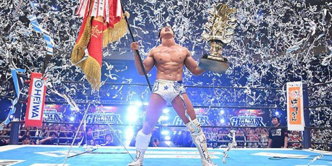 Kota Ibushi depois de vencer o G1 Climax do New Japan Pro Wrestling, segurando um estandarte e um grande troféu no ringue enquanto chovia confete.