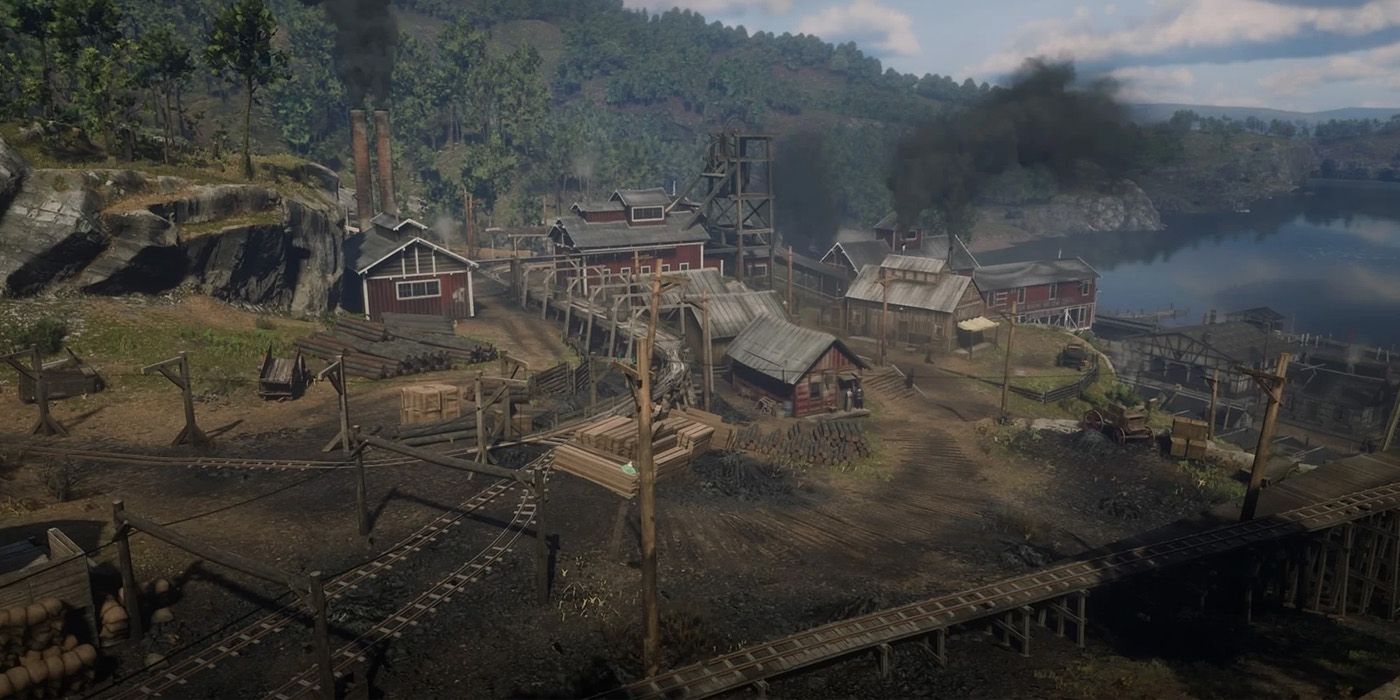An aerial view of Annesburg town in Red Dead Redemption 2, featuring numerous houses painted red with chimneys that release black smoke.