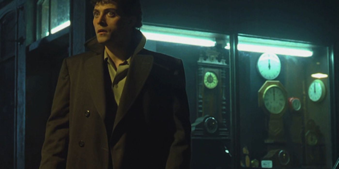 Rufus Sewell as John Murdoch standing near a clock shop in Dark City