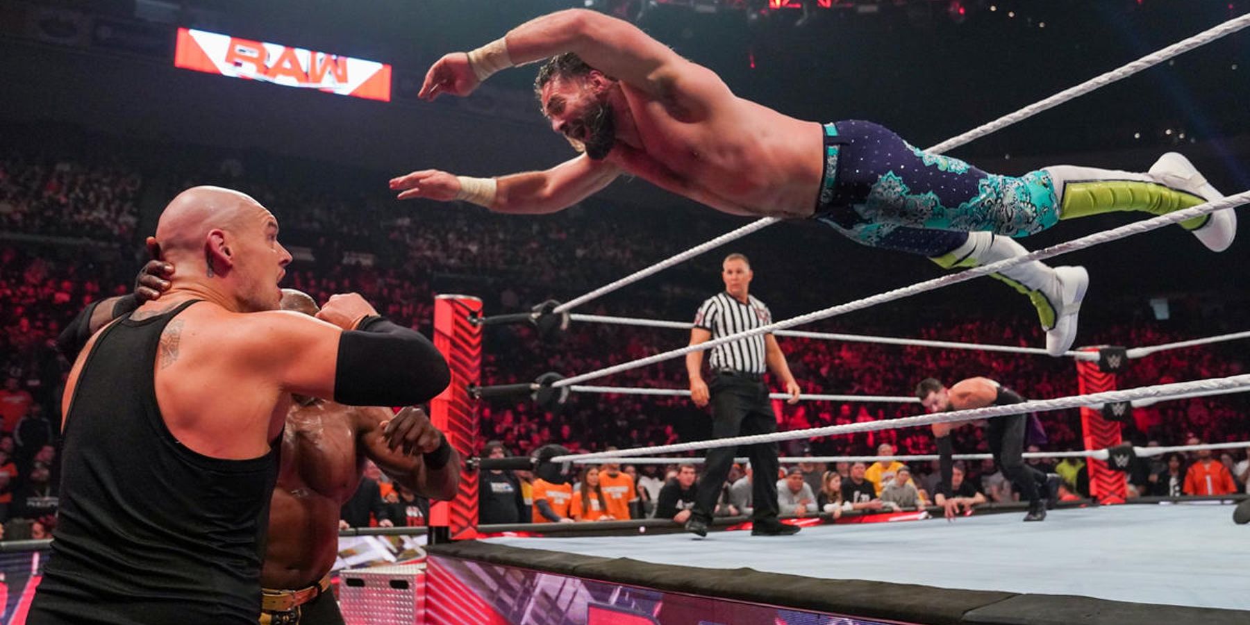 Seth Rollins navigue entre les cordes du haut et du milieu pour atterrir sur Baron Corbin et Bobby Lashley lors d'un épisode de WWE Raw en 2023.