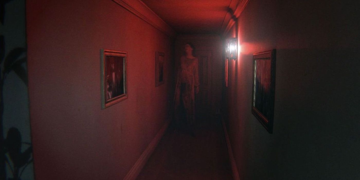 The ghost Lisa stands at the end of a hallway, illuminated in red light, in a P.T. screenshot