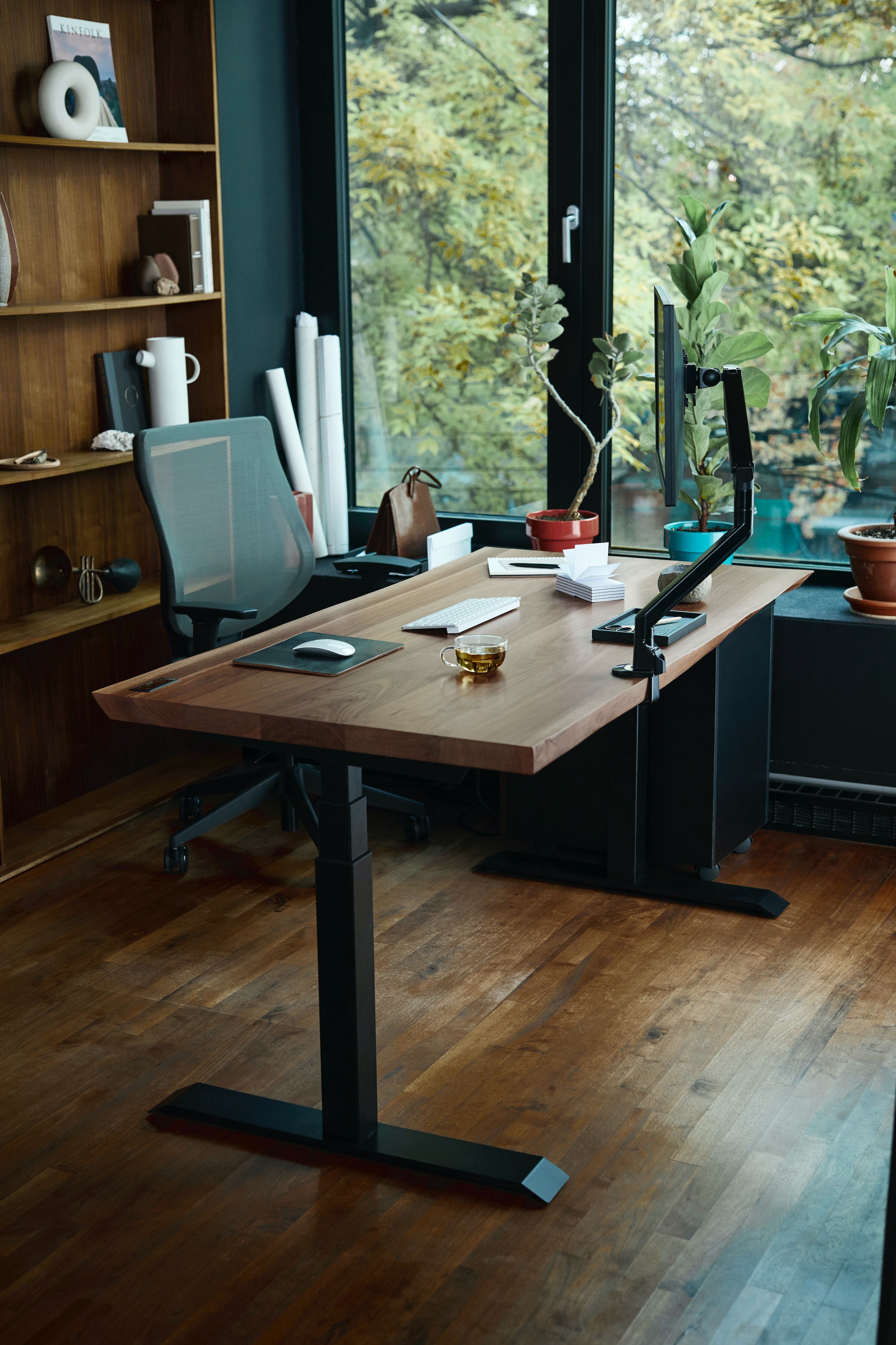 Standing desk and chair beside window