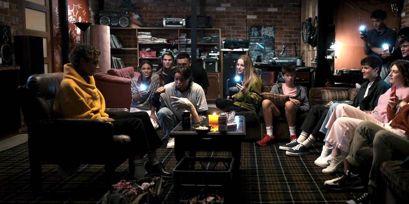 Students sit around a table with a creepy hand in Talk to Me