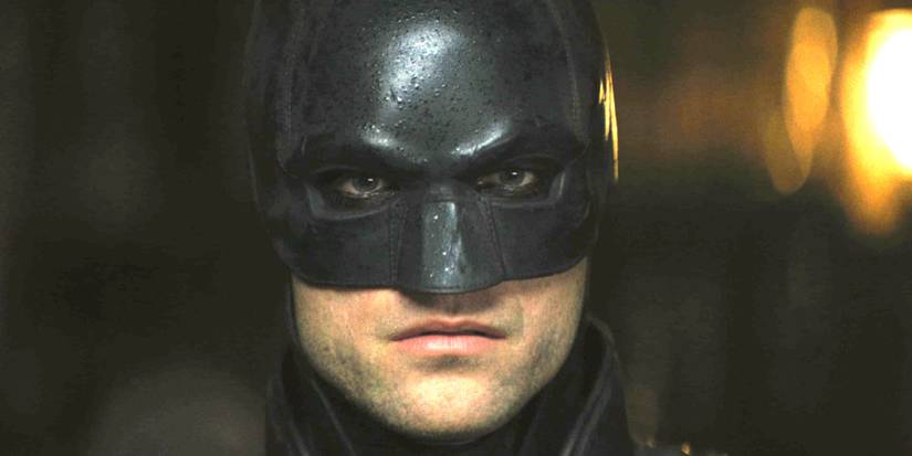 Robert Pattinson in The Batman wearing the iconic Batman mask and looking straight into the camera