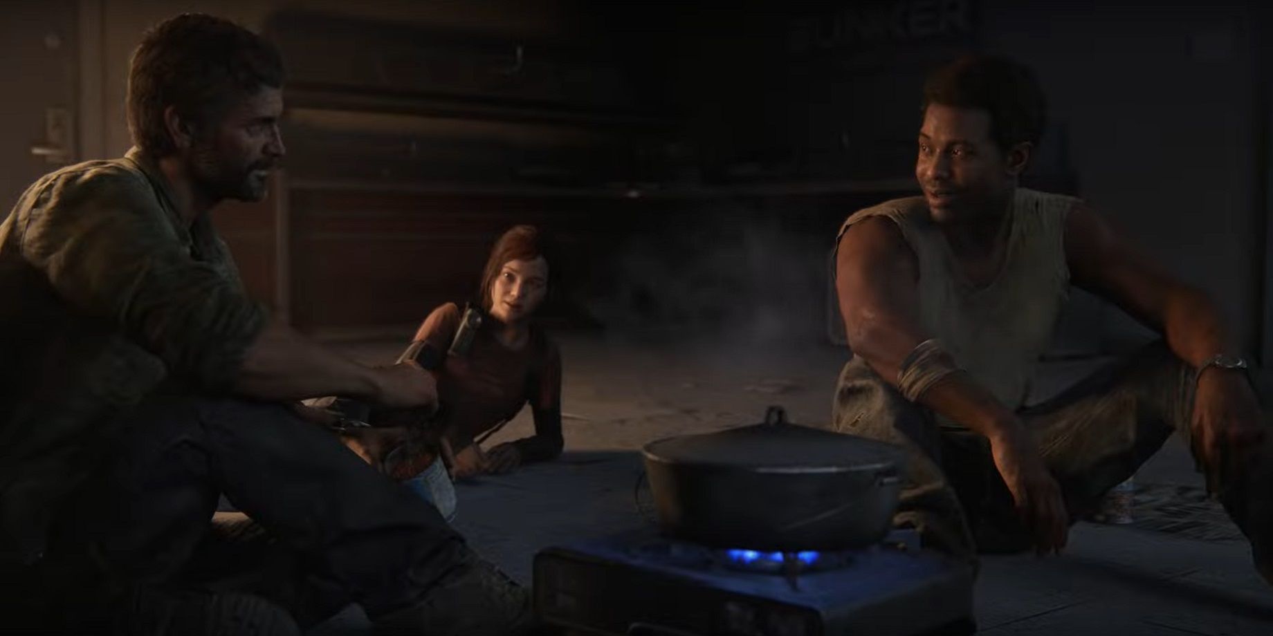 Henry talks and bonds with Joel and Ellie in The Last of Us Part 1 as the three sit around a small gas cooker fire in an abandoned room 