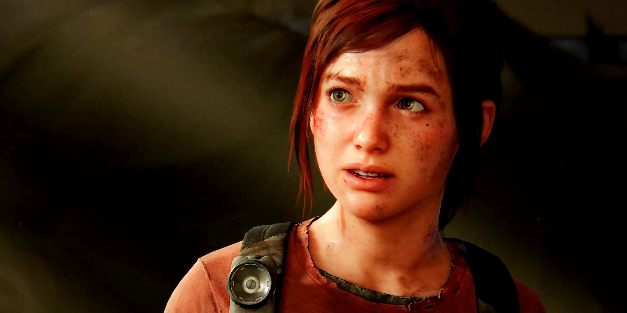 A screenshot of Ellie from The Last of Us Part 1 as she's looking concerned during a conversation with Joel. Light streaming in through boarded windows slants behind her, leaving the far side of her head in shadow.