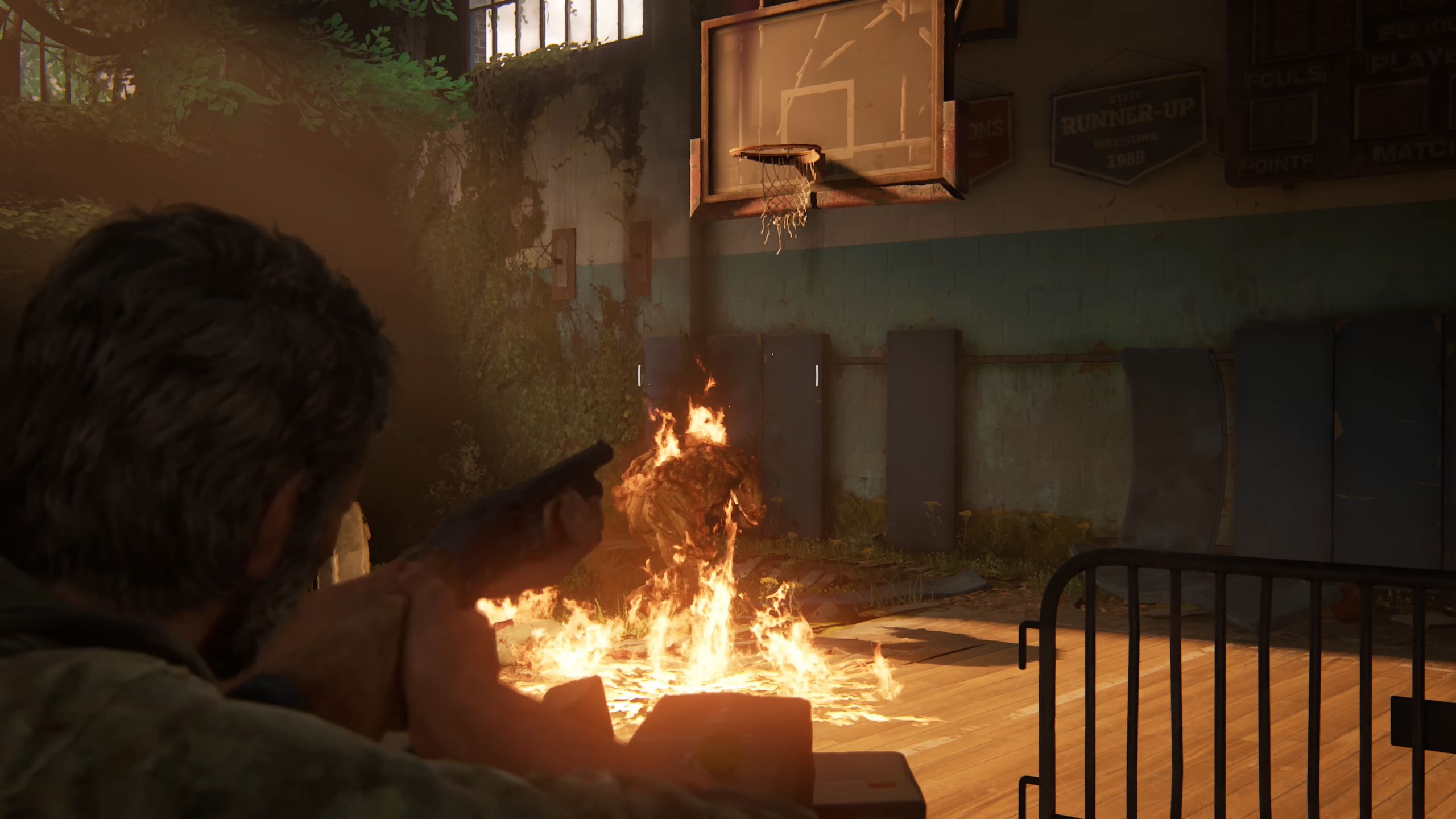 The Last Of Us Part I Joel mirando a espingarda em Burning Bloater no ginásio da escola de Bill's Town
