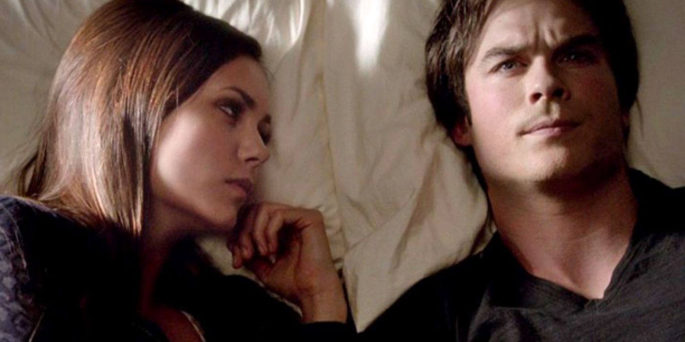Elena staring at Damon as she lies next to him in bed in The Vampire Diaries