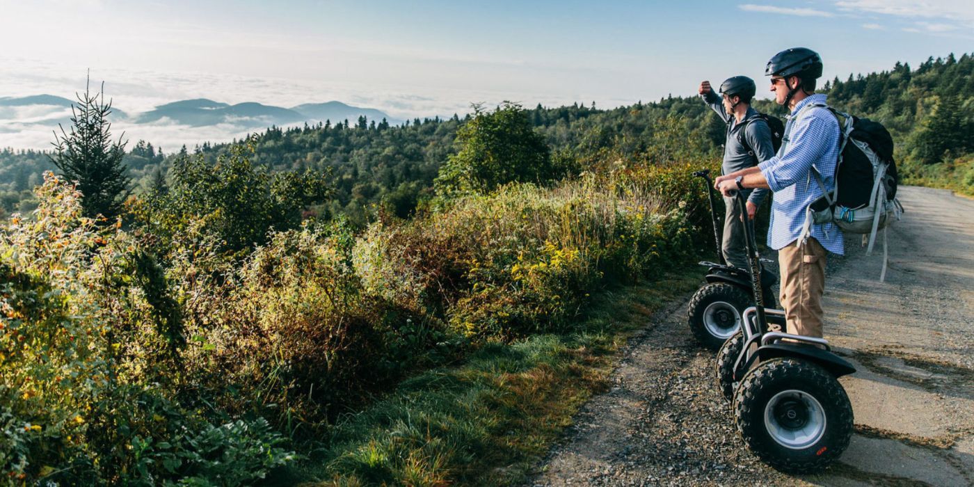 Two men on Segways look out at the view in a park