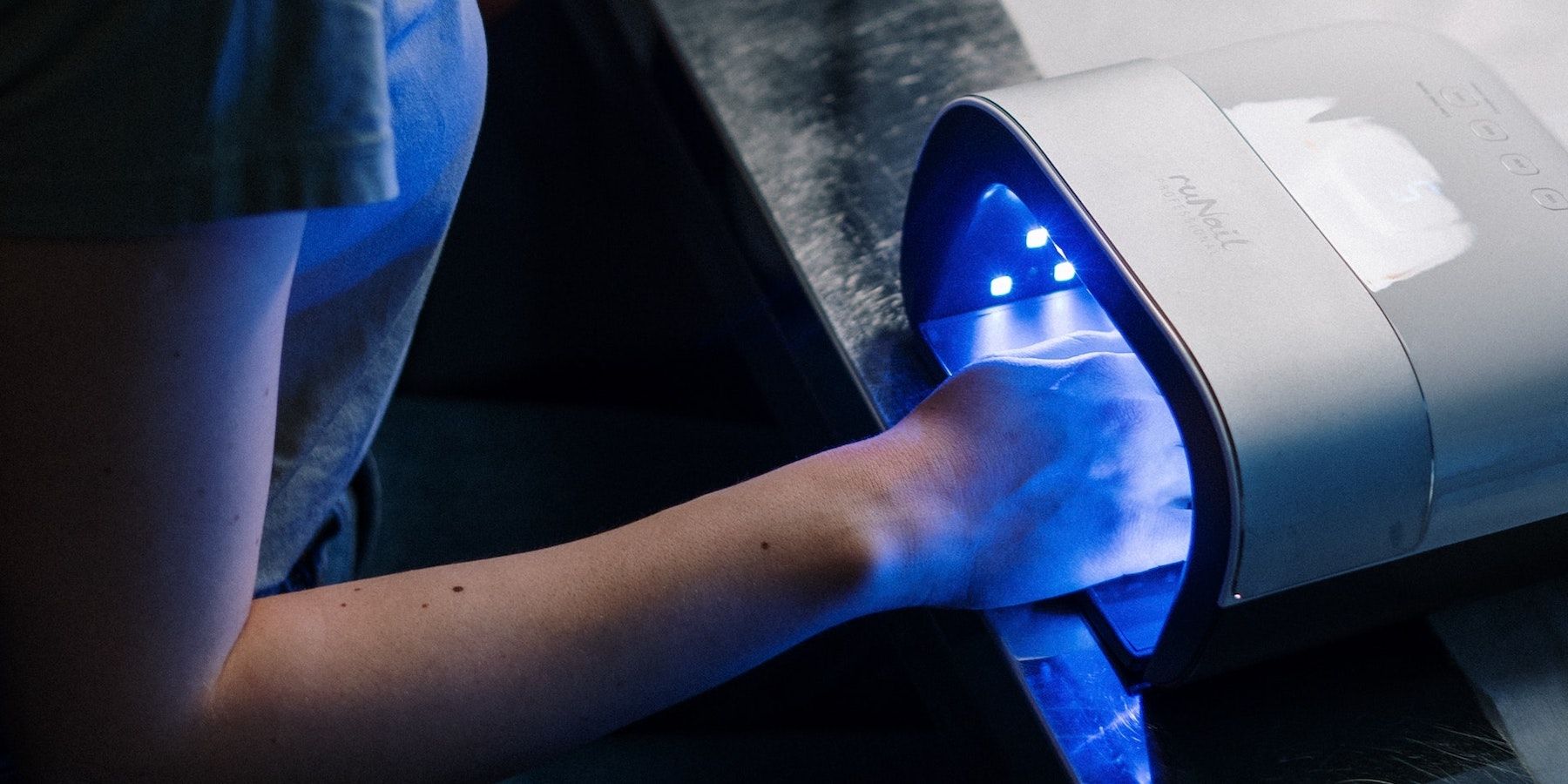 A woman using a UV nail polish dryer