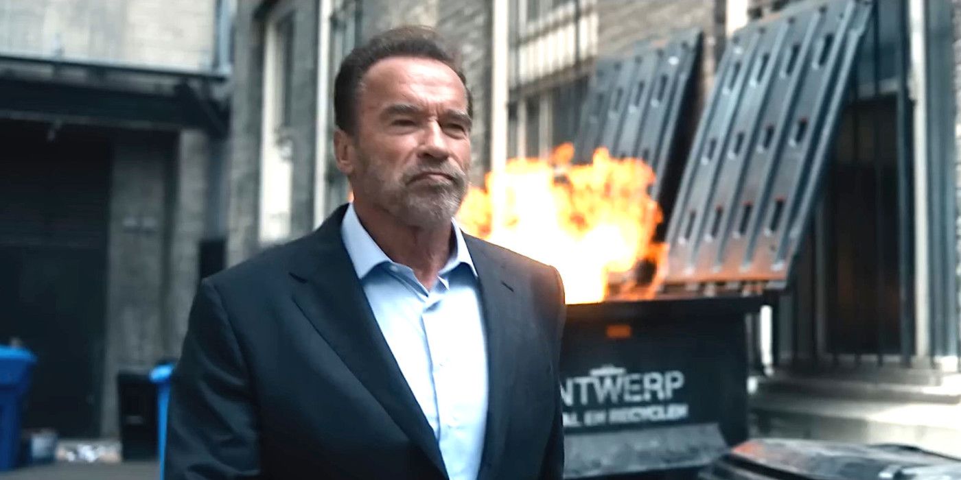 Arnold Schwarzenegger In FUBAR making a tough face while walking down a dirty alley with a dumpster fire happening in the background