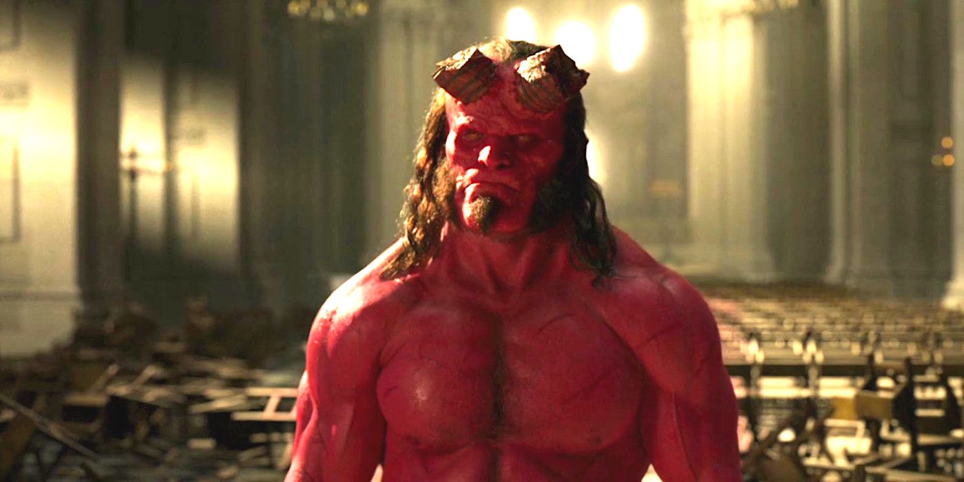 In Hell David Harbor Reboot all demonic red with big veined muscles and severed horns, scowling at a giant church with white marble pillars and chairs in the background.