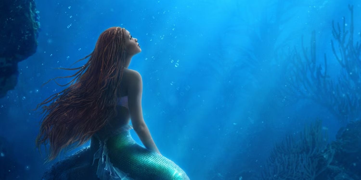 Halle Bailey as Ariel in The Little Mermaid Movie Poster looking up at the edge of the ocean