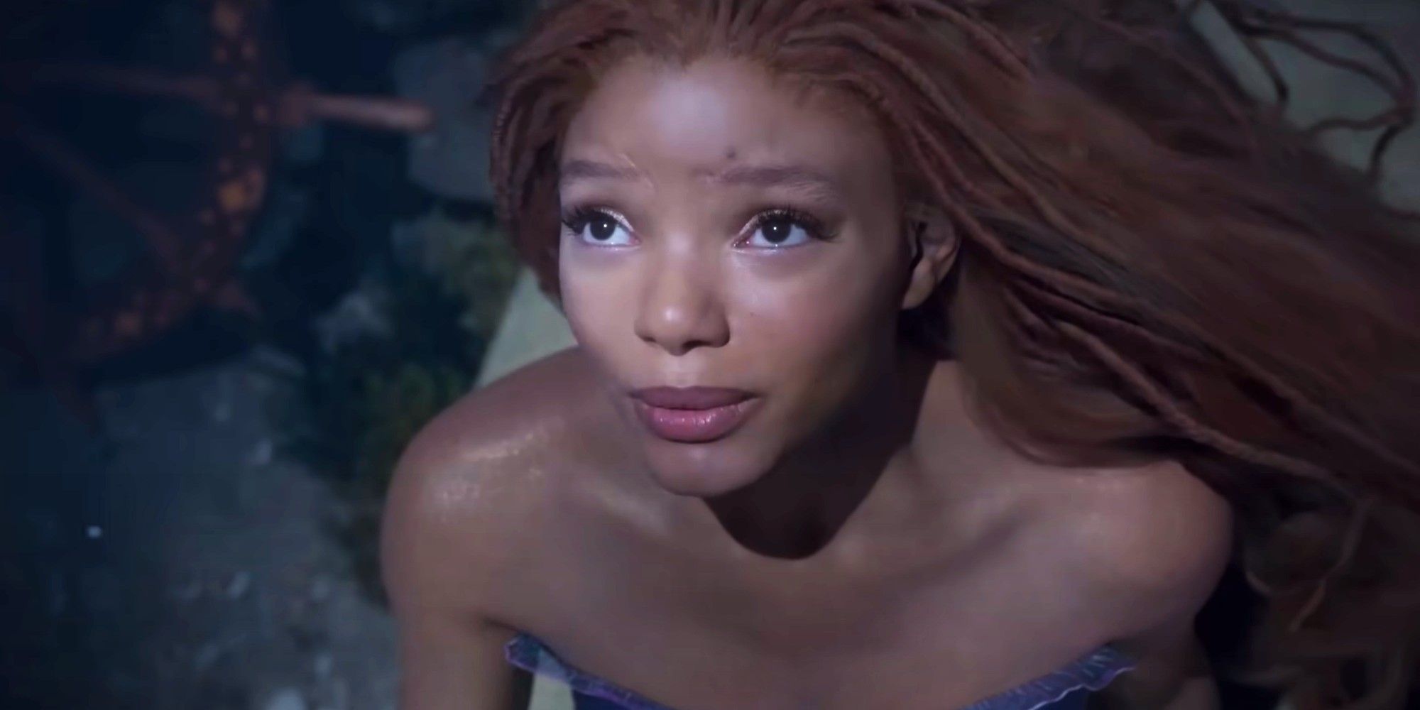 Halle Bailey as Ariel singing and looking up at the ocean edge in The Little Mermaid