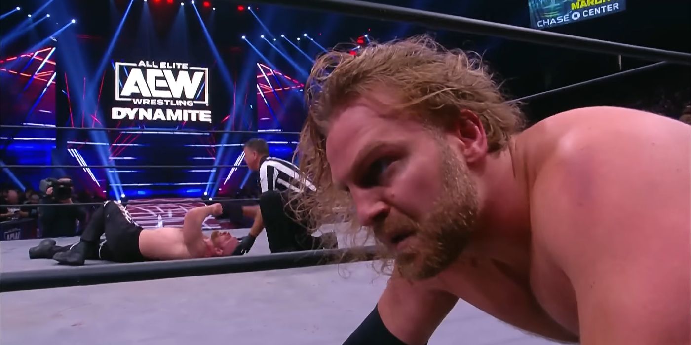 Hangman Adam Page settles on the ring apron, contemplating how to finish off Jon Moxley during their match on AEW Dynamite in 2023.