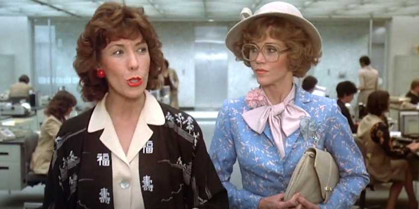 Lily Tomlin and Jane Fonda in Nine to Five doing a walk and talk through a bustling office