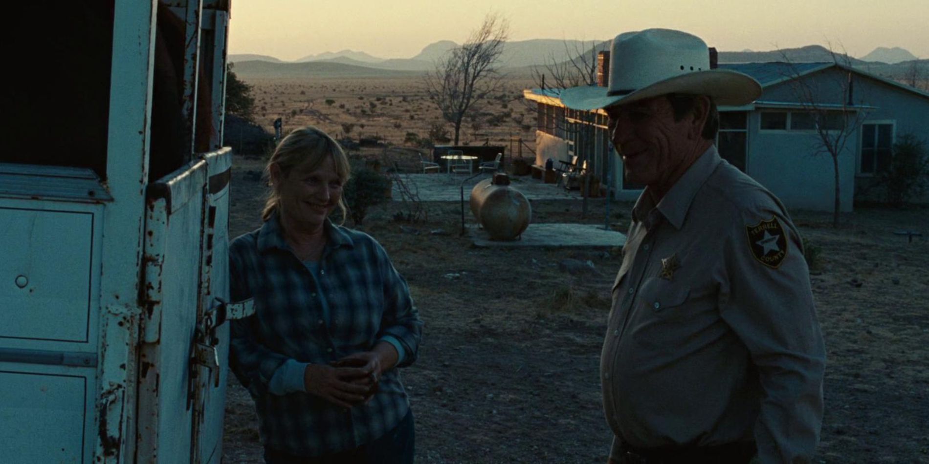 Loretta Bell leaning on a wall and Ed Tom Bell in No Country for Old Men.