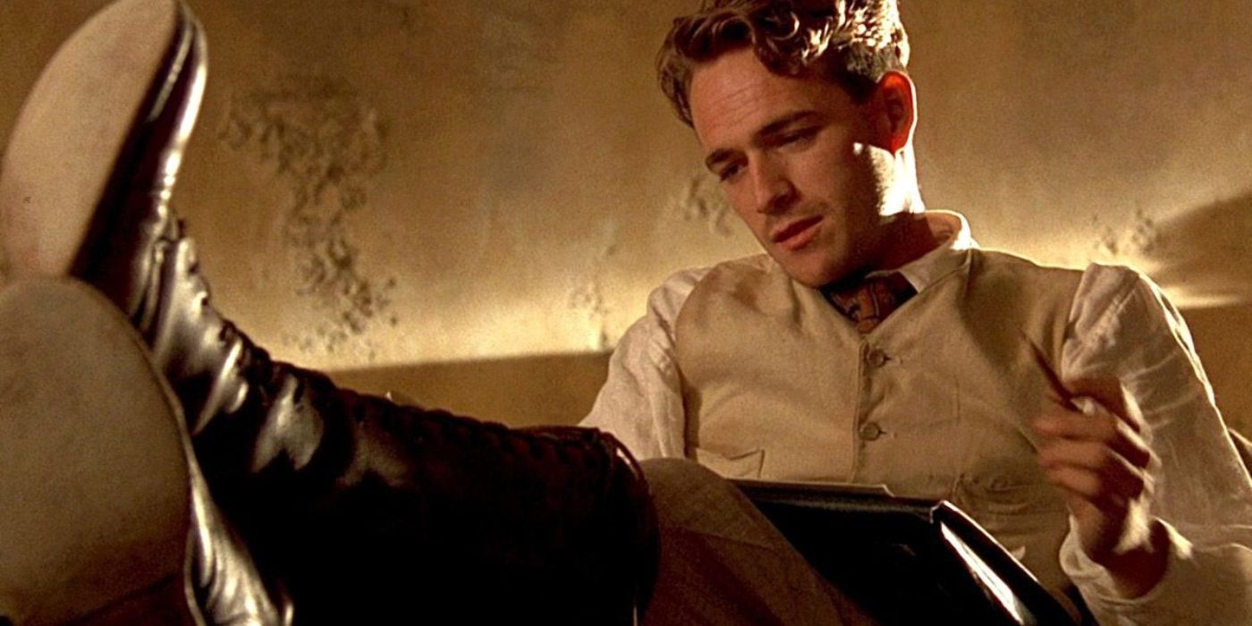 Luke Perry as Billy sitting down and writing in The Fifth Element