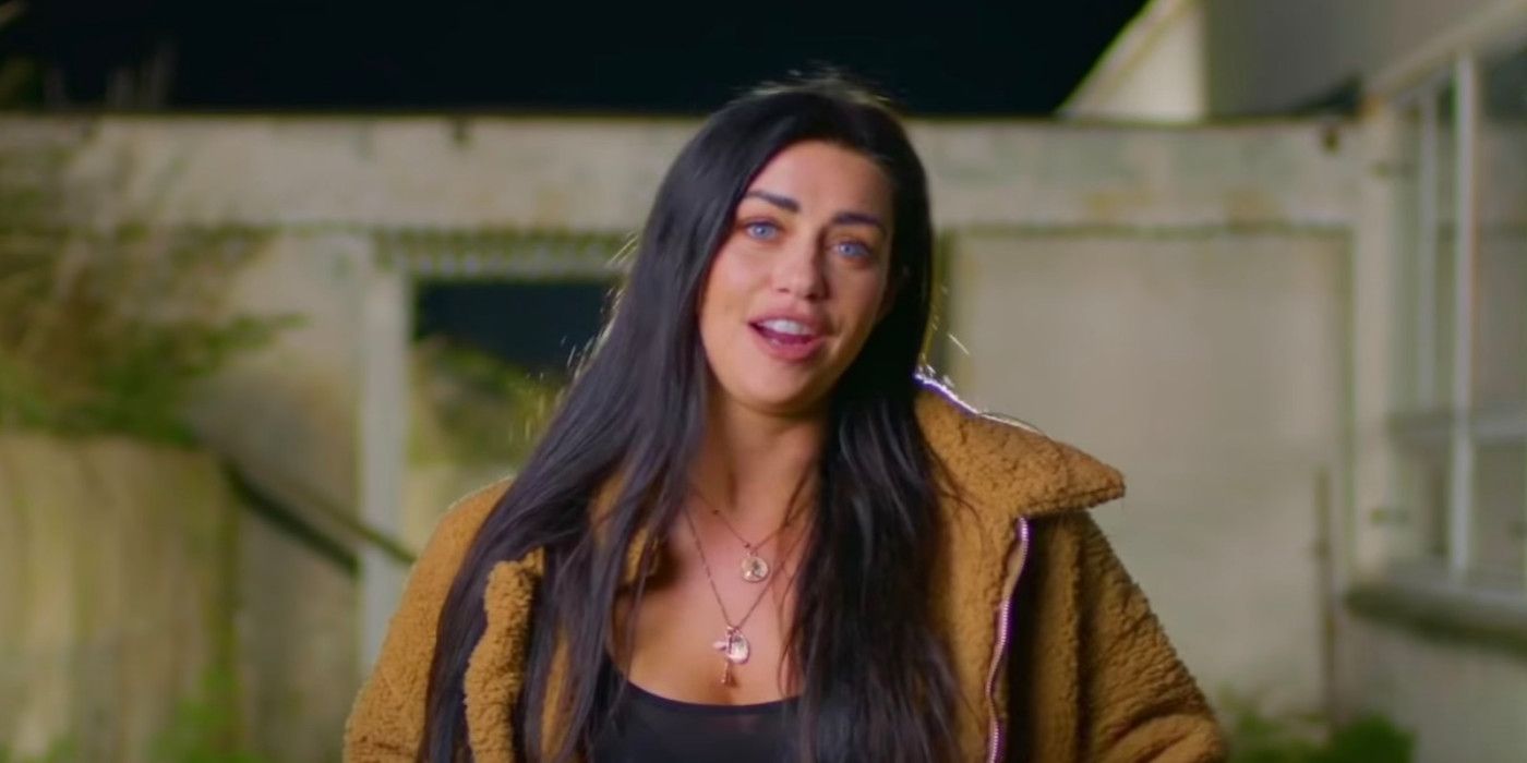 Mattie Breaux from Floribama Shore. She is wearing an orange jacket and two long necklaces, with her long black hair loose over her shoulders. 