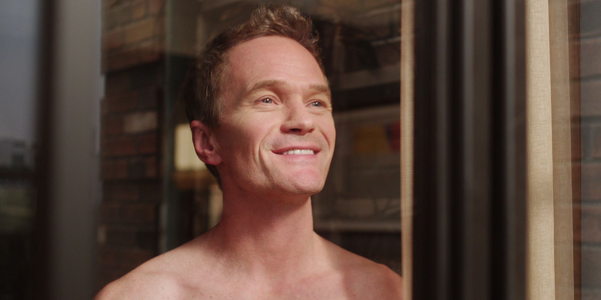 Neil Patrick Harris olhando pela janela sem camisa e sorrindo em desacoplado