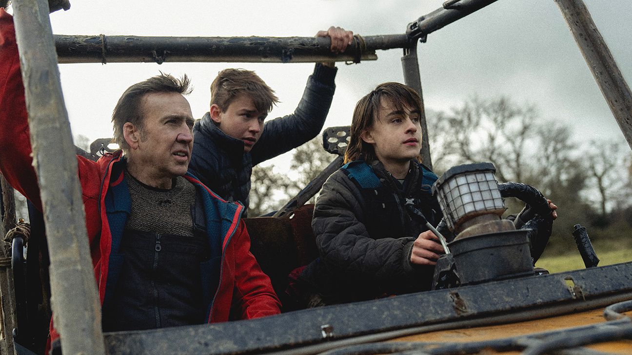 Nicolas Cage rides with two kids in an open air vehicle in a forest setting