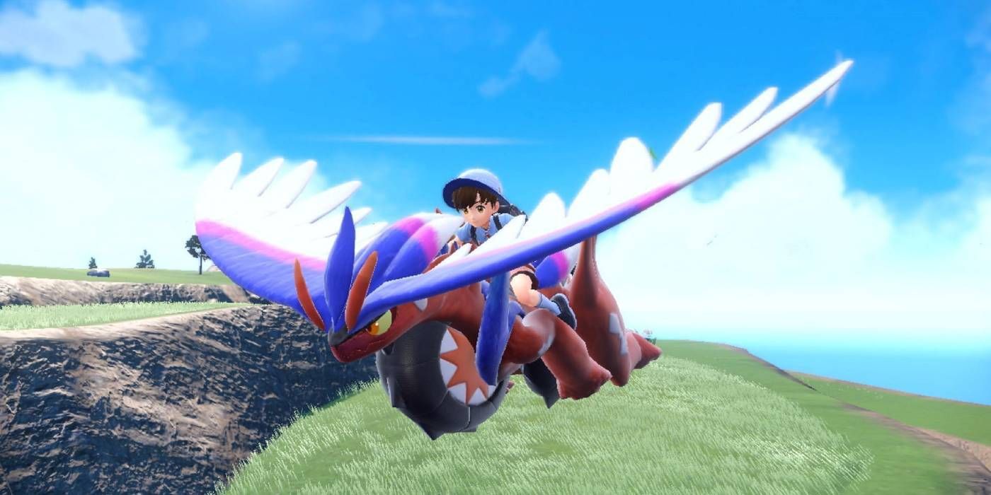 A Pokémon Trainer riding on the back of Koraidon as it flies in Pokémon Scarlet and Violet.