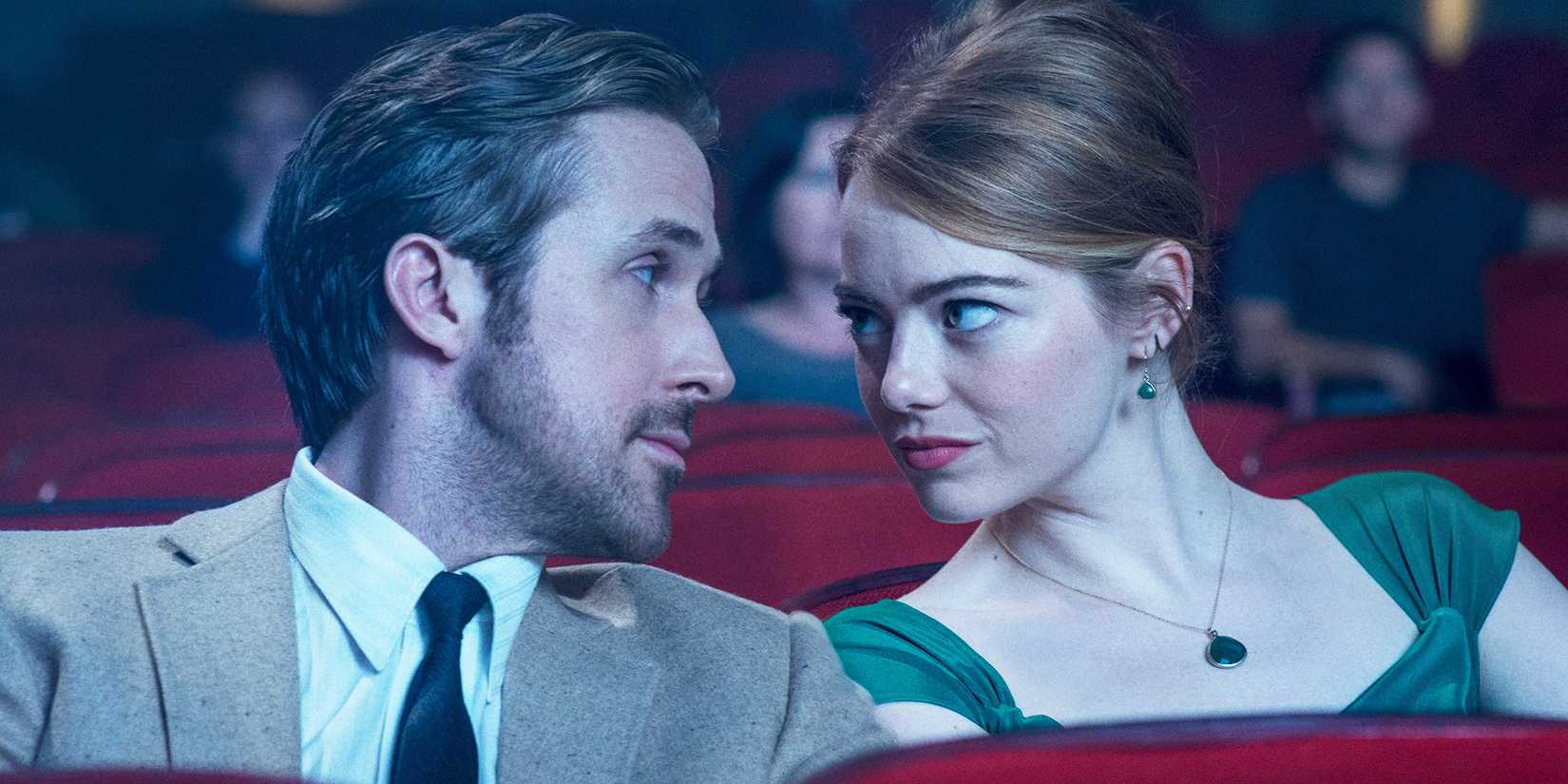 Ryan Gosling as Seb and Emma Stone as Mia looking at each other in a movie theater in La La Land