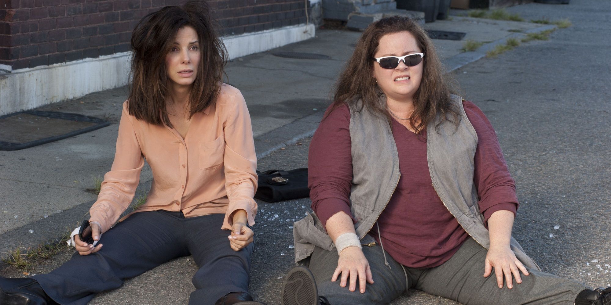 Sandra Bullock and Melissa McCarthy sitting on the street in The Heat