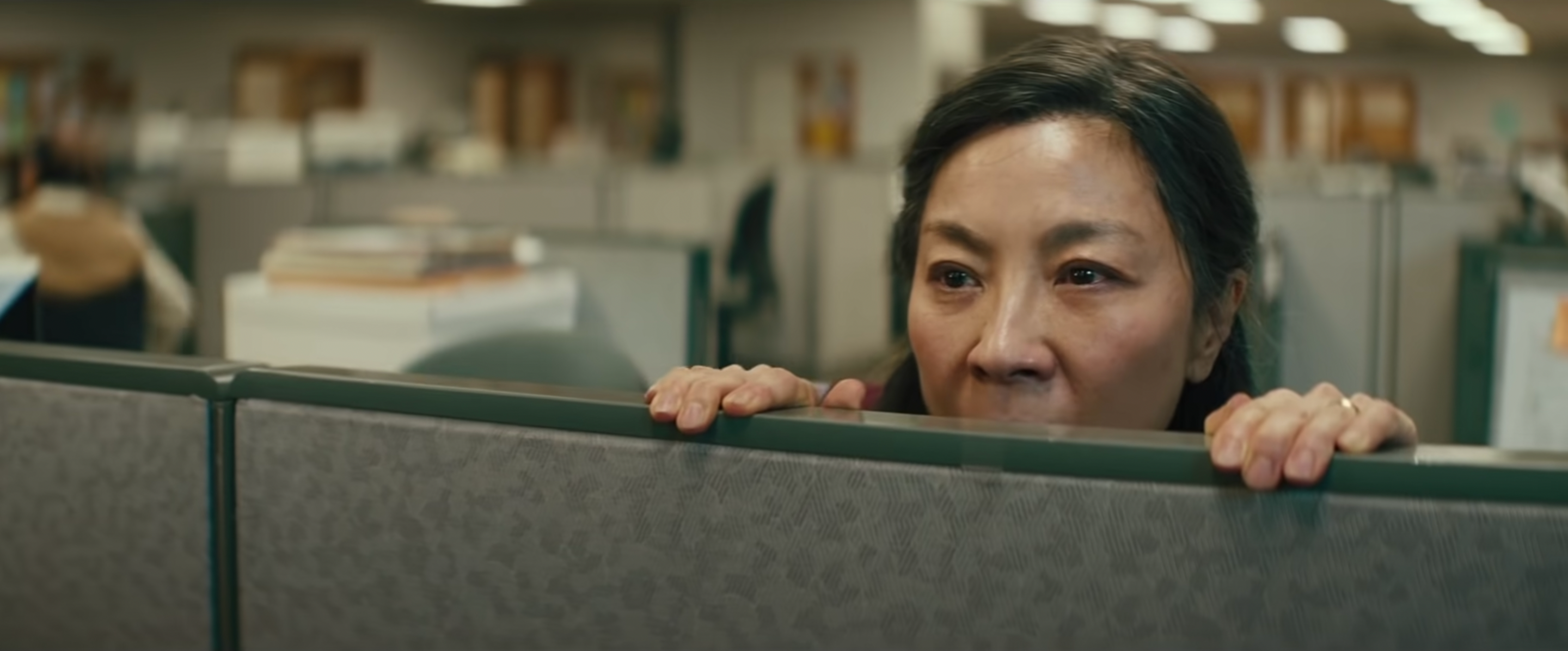 Quan looking over an office barrier in Everything Everywhere All At Once
