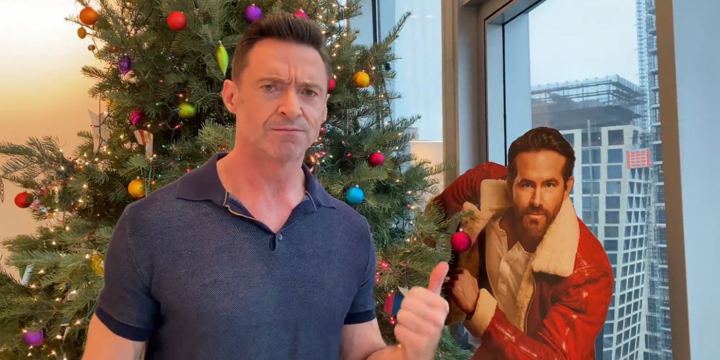 Hugh Jackman pointing angrily at a cardboard cutout of Ryan Reynolds near his Christmas Tree