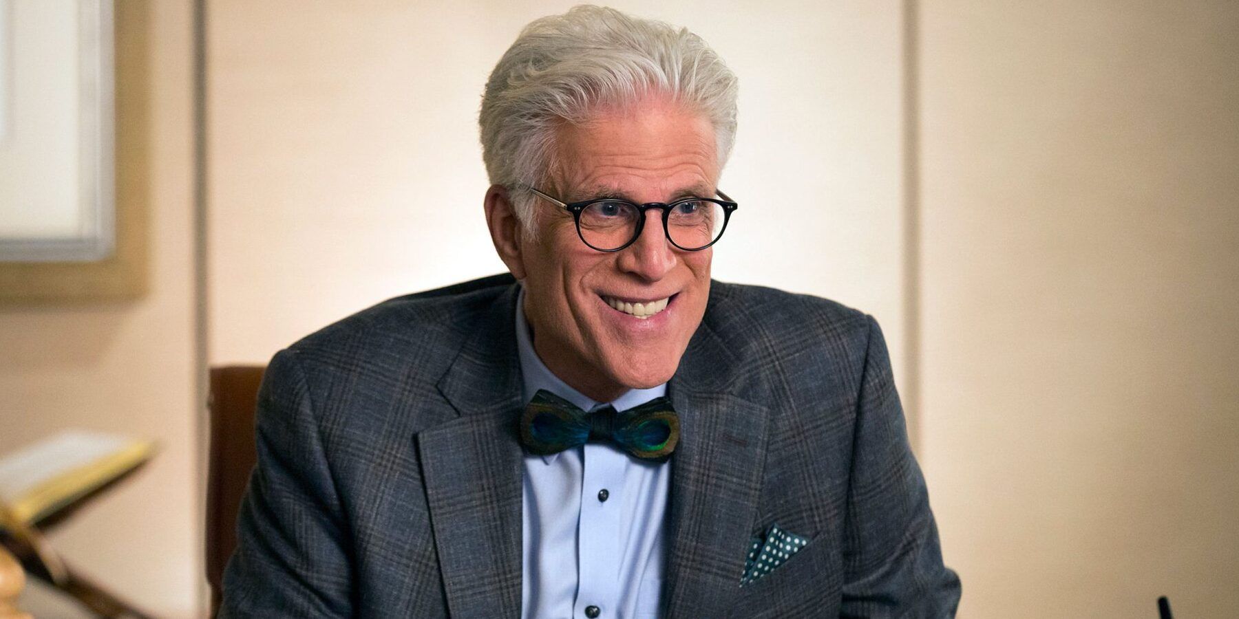 Ted Danson in The Good Place smiling at someone while wearing a bow tie and suit