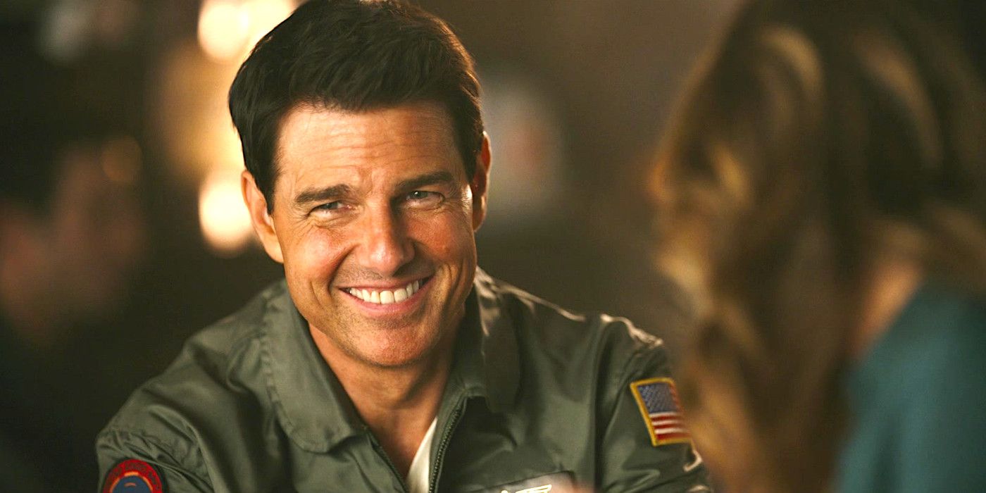 Tom Cruise as Maverick in Top Gun 2 in a bar wearing a jacket with military patches and smiling happily