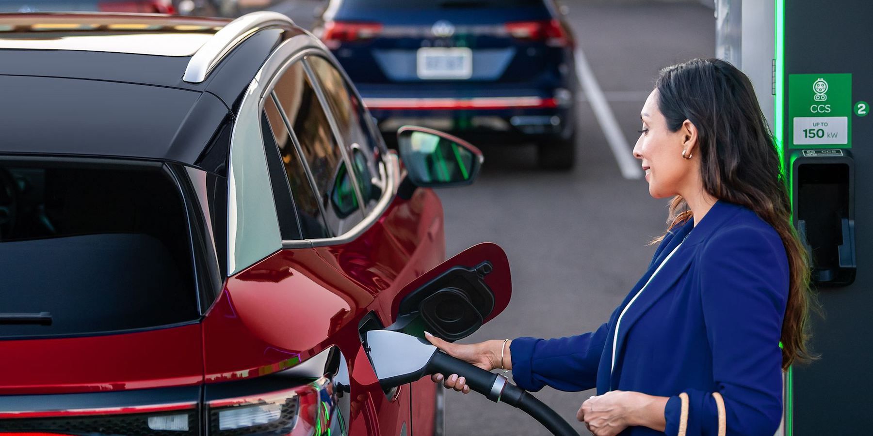 A woman charging the Volkswagen ID.4 at an Electrify America public charger