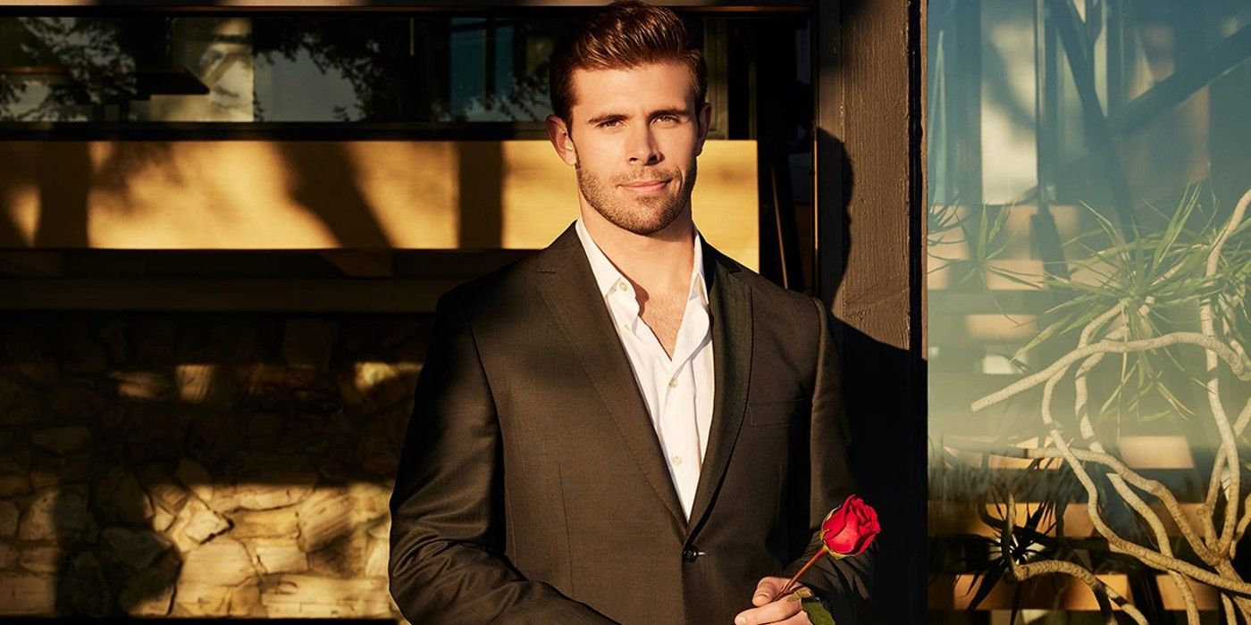 Zach Shallcross from The Bachelor in a black suit and holding a rose