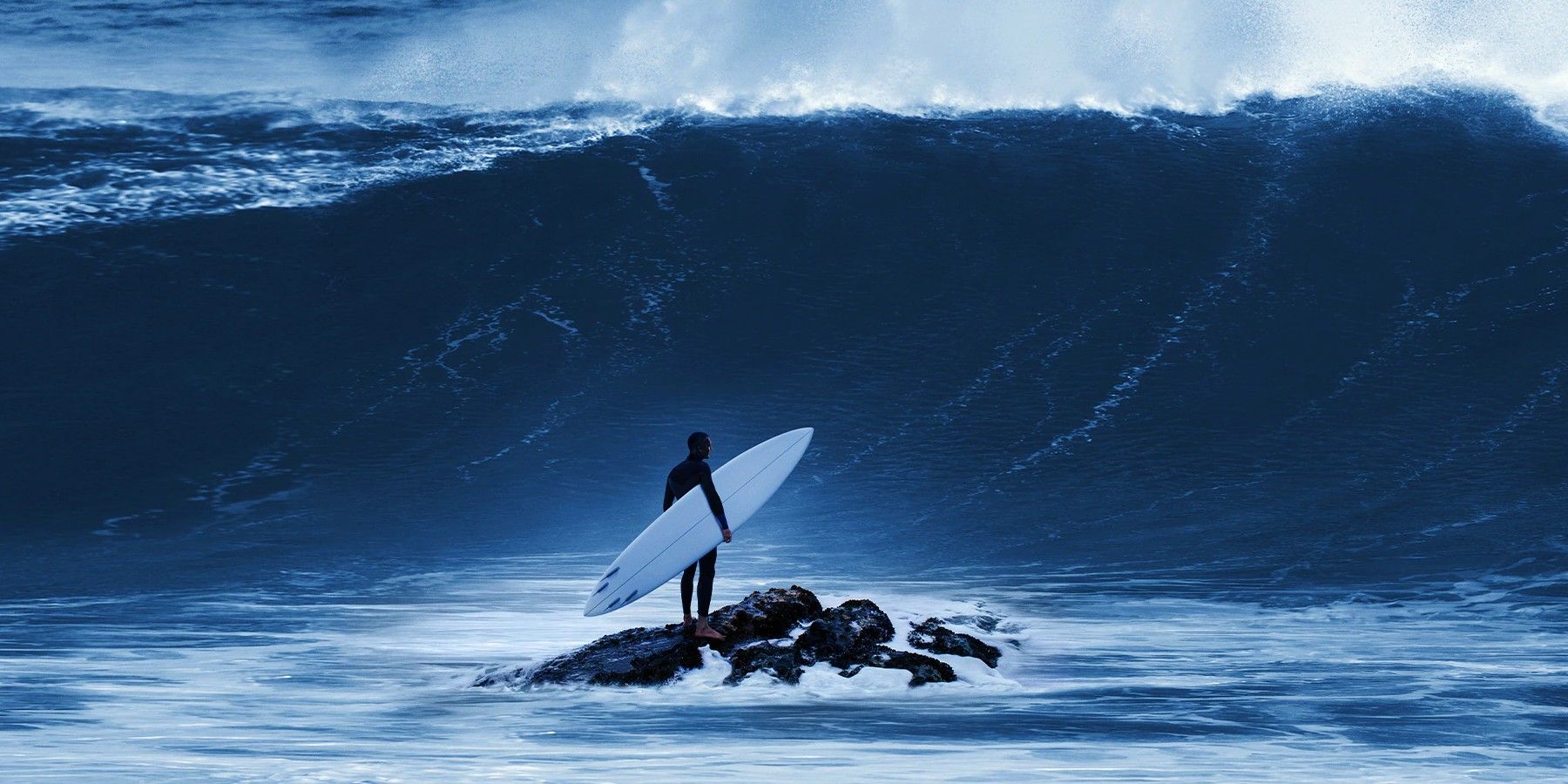 Man standing on a rock looking at a wave in 100 Foot Wave