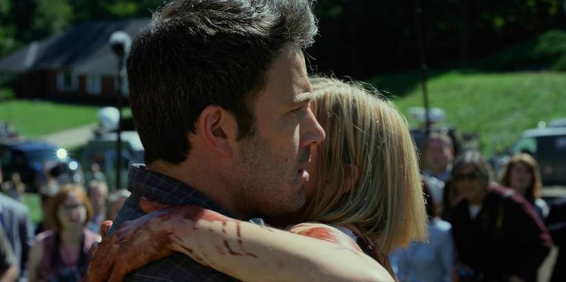 Amy (Rosamund Pike) comes home to Nick (Ben Affleck) and they embrace in Gone Girl