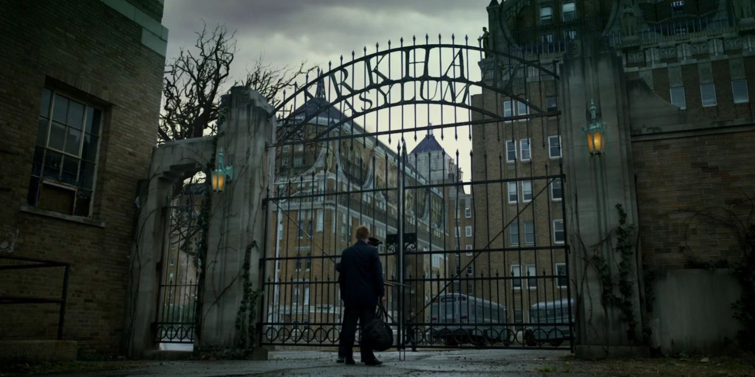 An image of a man standing outside Arkham Asylum gates