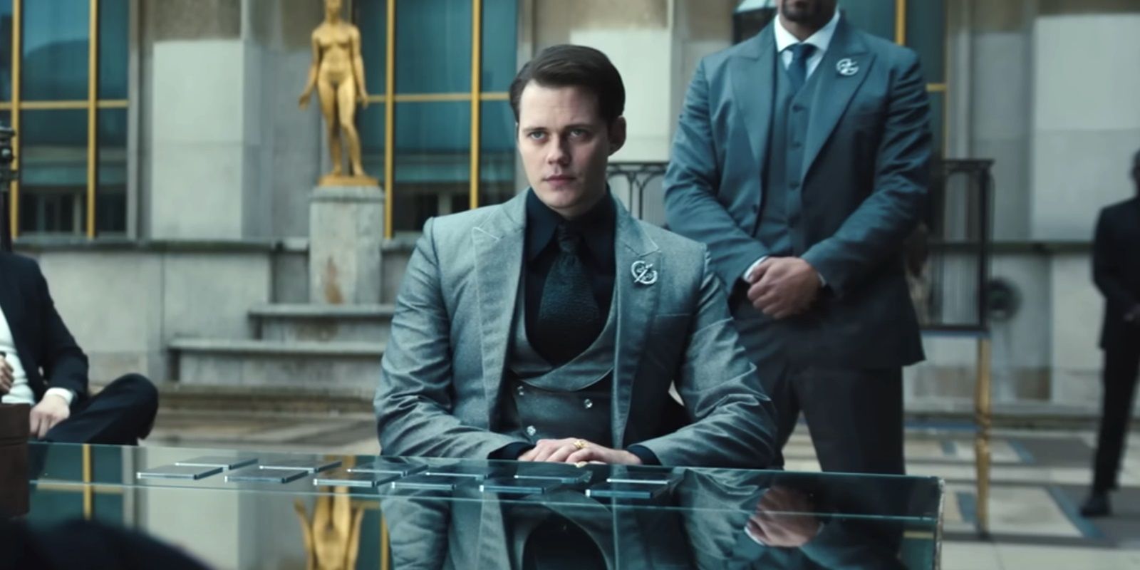 Bill Skarsgard sits at a table in John Wick Chapter 4