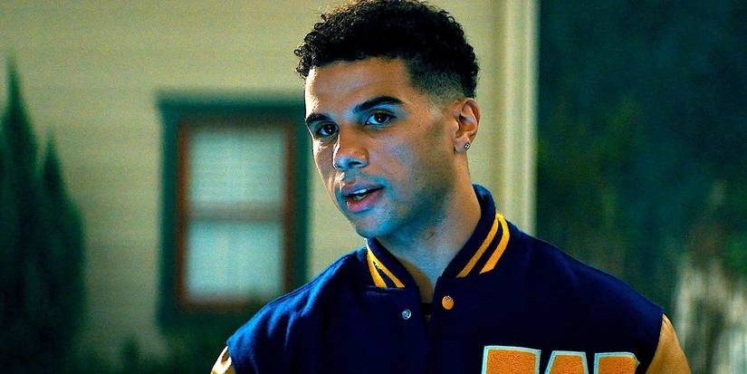 Mason Gooding's Chad Meeks Martin wearing a yellow and blue jacket while outside looking around in Scream 5