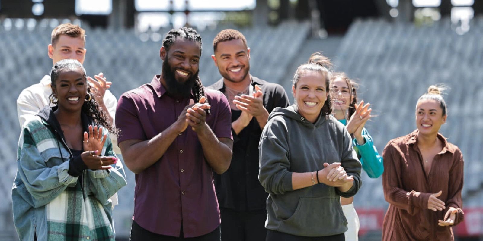 Some of the global MVPs from The Challenge: World Championship. They are standing in a group, all clapping and smiling, against a background of stadium seats.