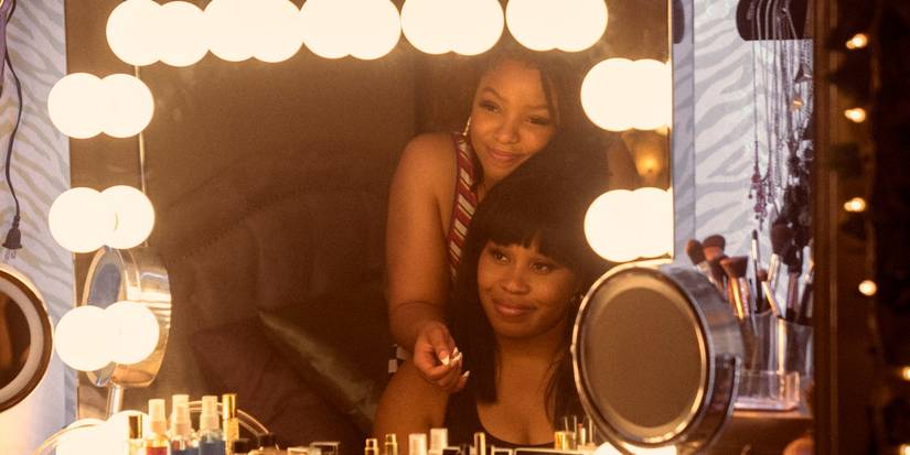 Chloe Bailey smiling at Dominique Fishback in the mirror in Swarm