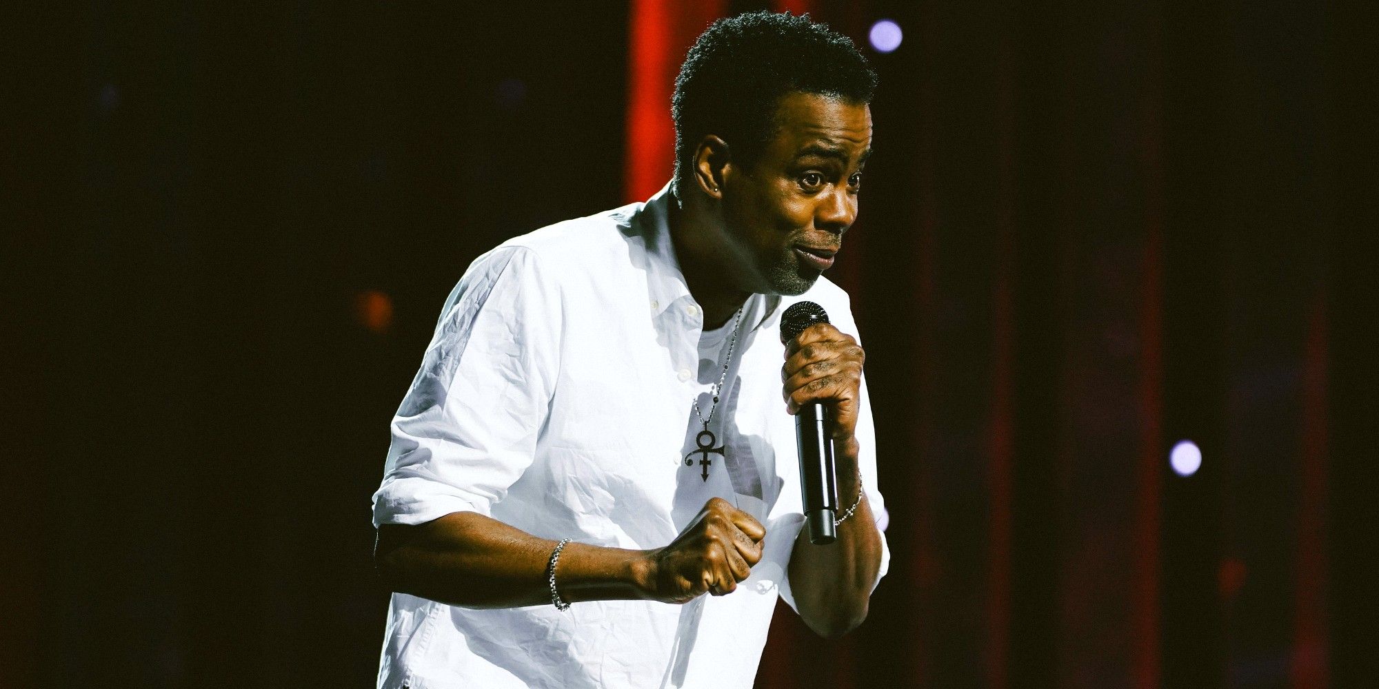 Chris Rock standing on stage and holding a microphone during Selective Outrage special on Netflix