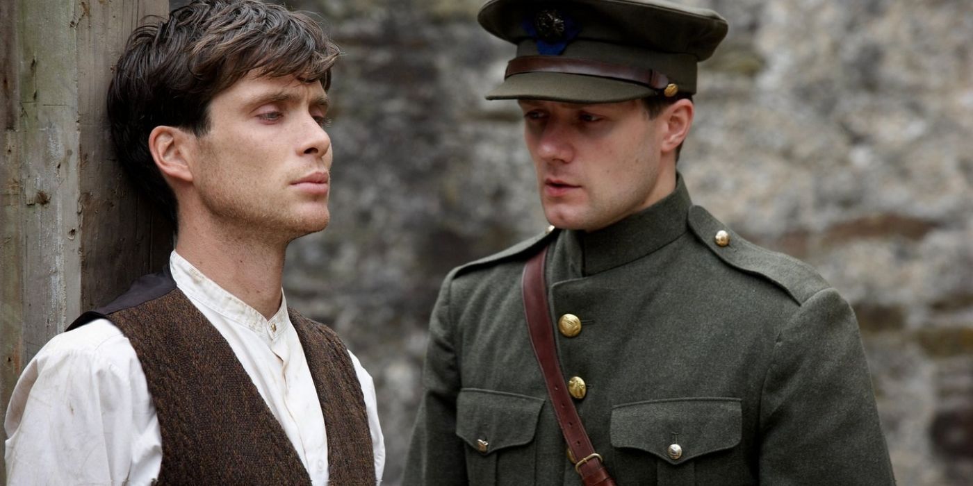 Cillian Murphy leaning against a wall while a soldier talks to him in The Wind That Shakes The Barley.