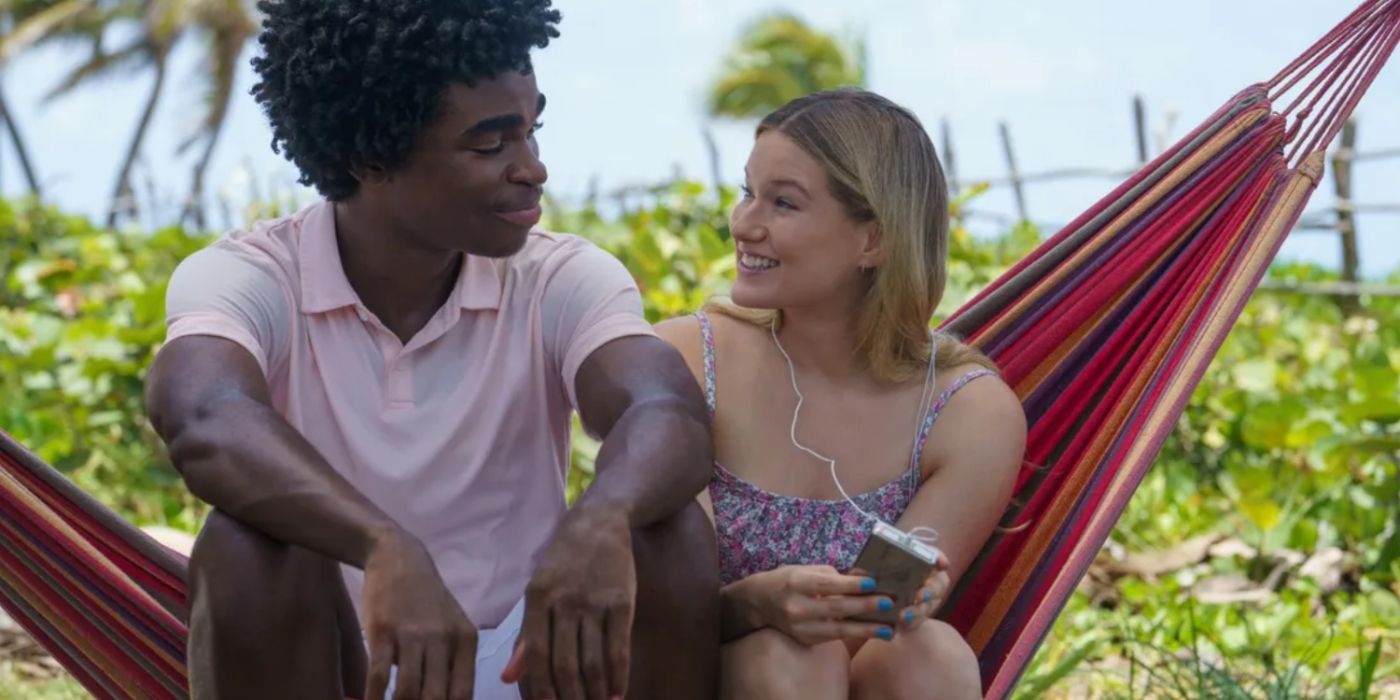 A young man and woman sitting under a palm tree in Saint X