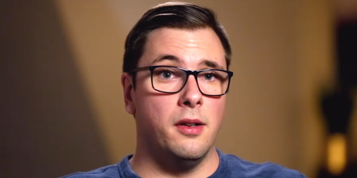 Colt Johnson from 90 Day Fiancé clean shaven with blue shirt in close up with brown background