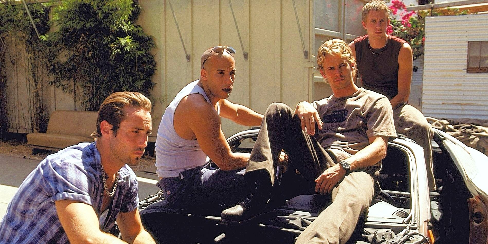 Dom and Brian sitting on a car with their friends in The Fast and the Furious 
