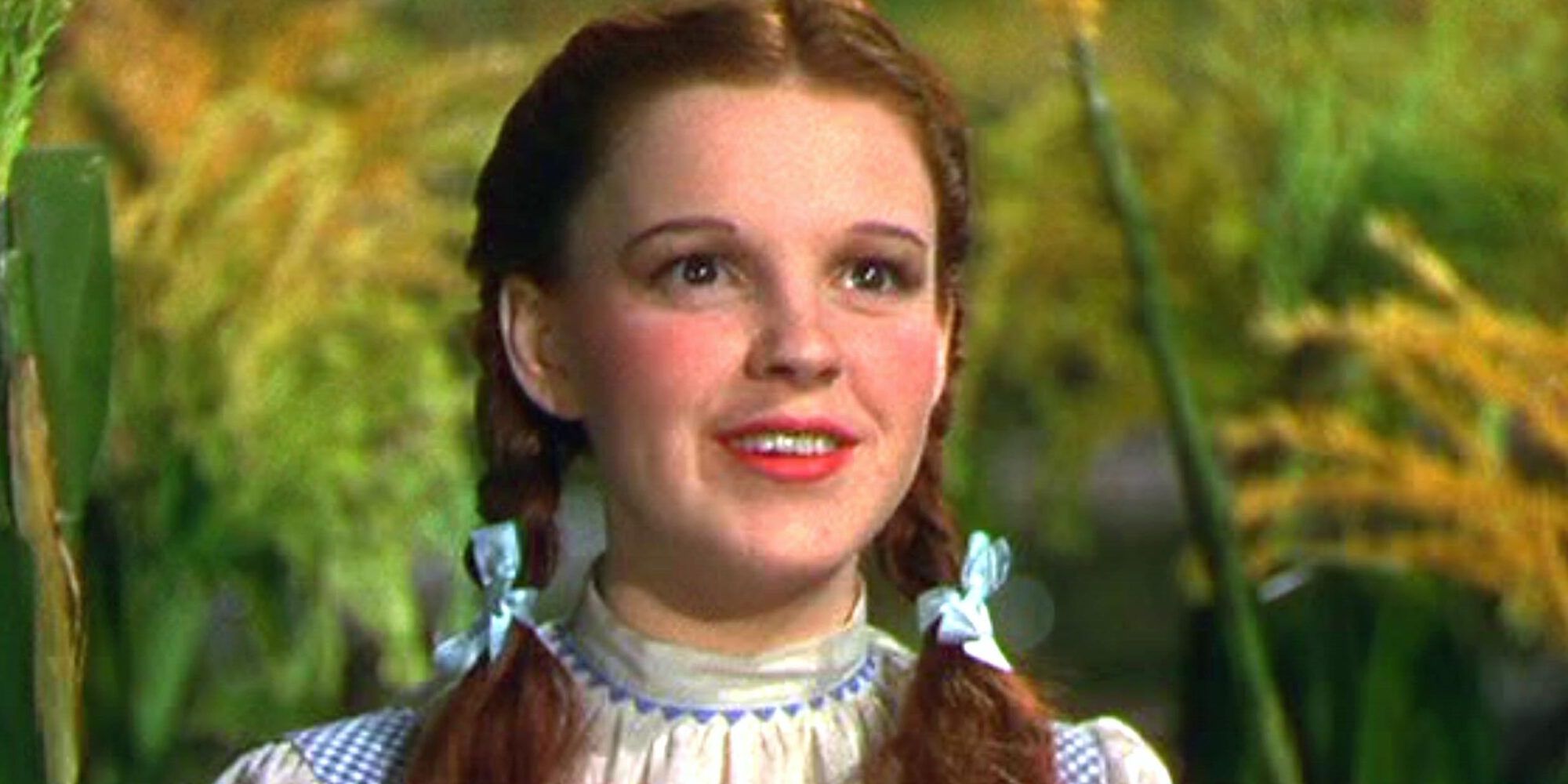 Dorothy sonriendo en El mago de Oz en un campo de maíz