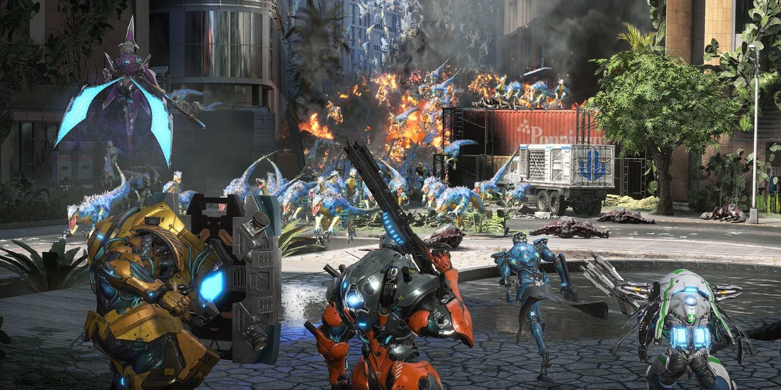 A team of exosuits are seen preparing to collide with a large wave of Exoprimal's raptors who are rushing towards the player through a city street, covered in fire and rubble.