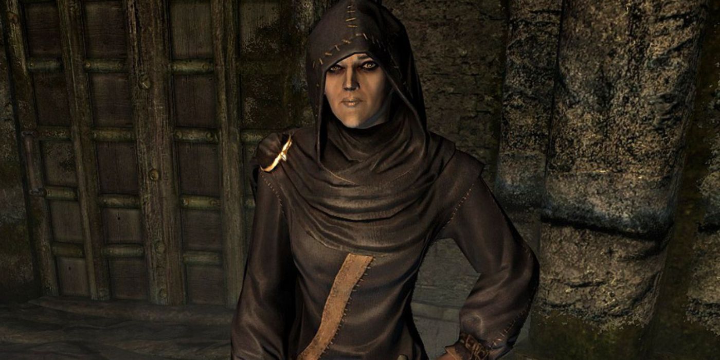 A close-up of the mage Illia from Skyrim wearing a dark hood and robes.
